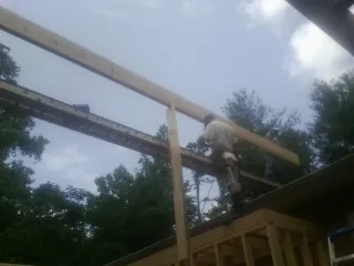 Carpenter setting a ridge beam over a new addition frame — Ice Dam Removal by Roofing Brothers in Osage City