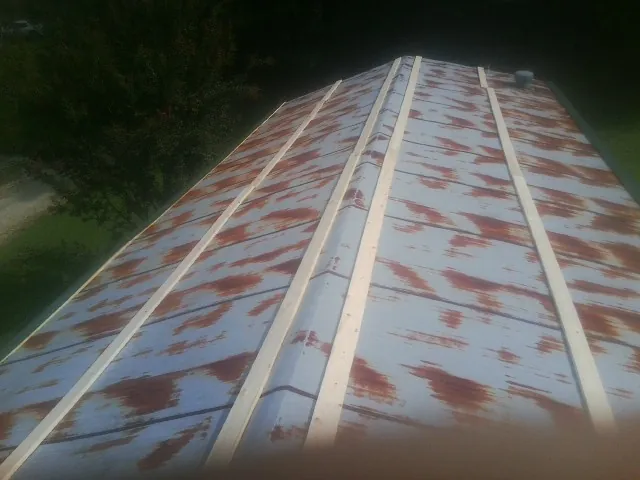 Rusted metal roof panels with new wood purlins before replacement — Storm Damage Roof Repair in Osage City by Roofing Brothers