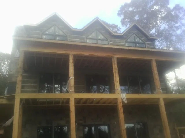 Dormers and porch framing on a large log home under construction — Roof Coating work by our crew in Osage City