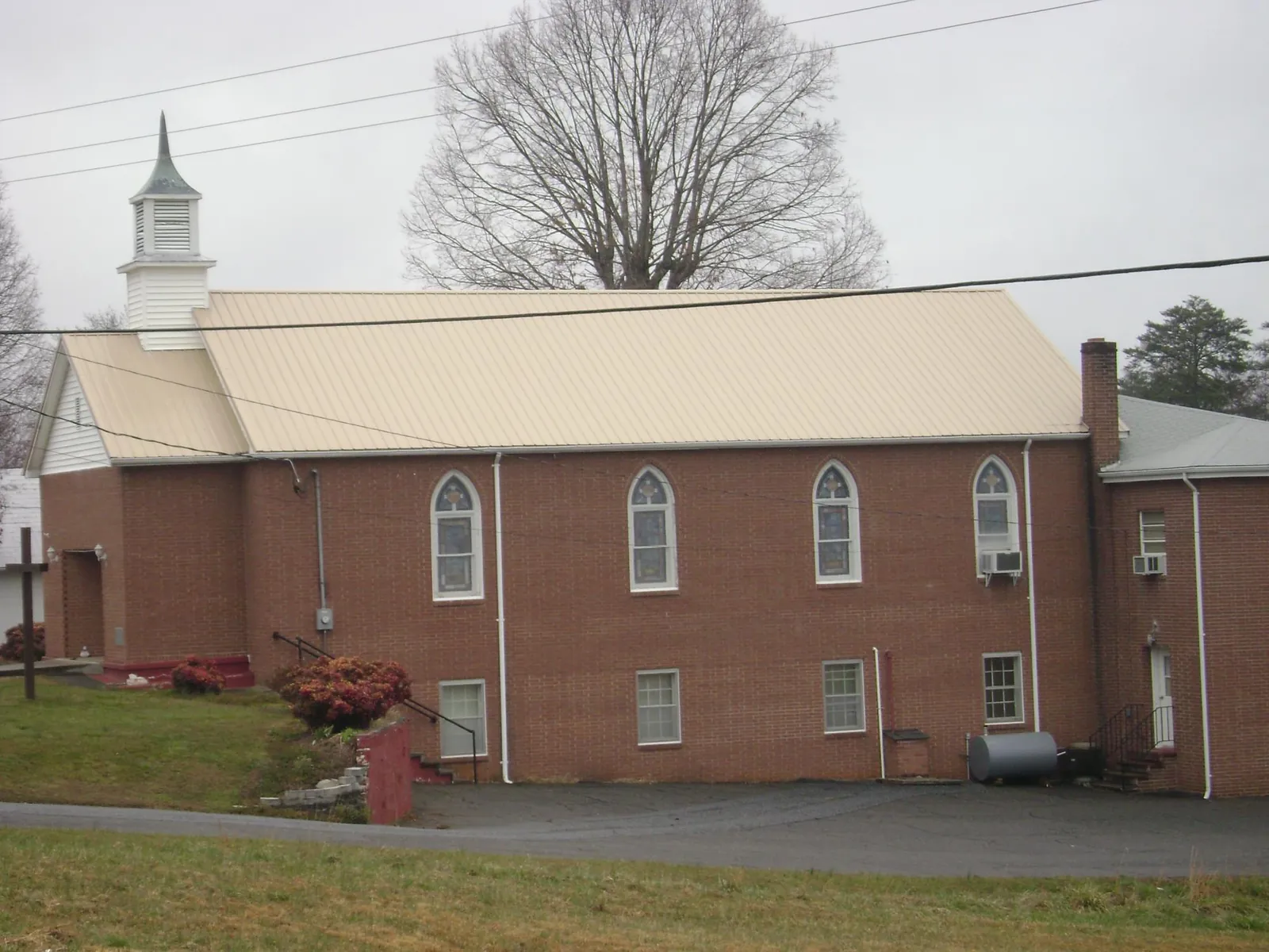 New tan metal roof on a brick church with a white steeple in Osage City