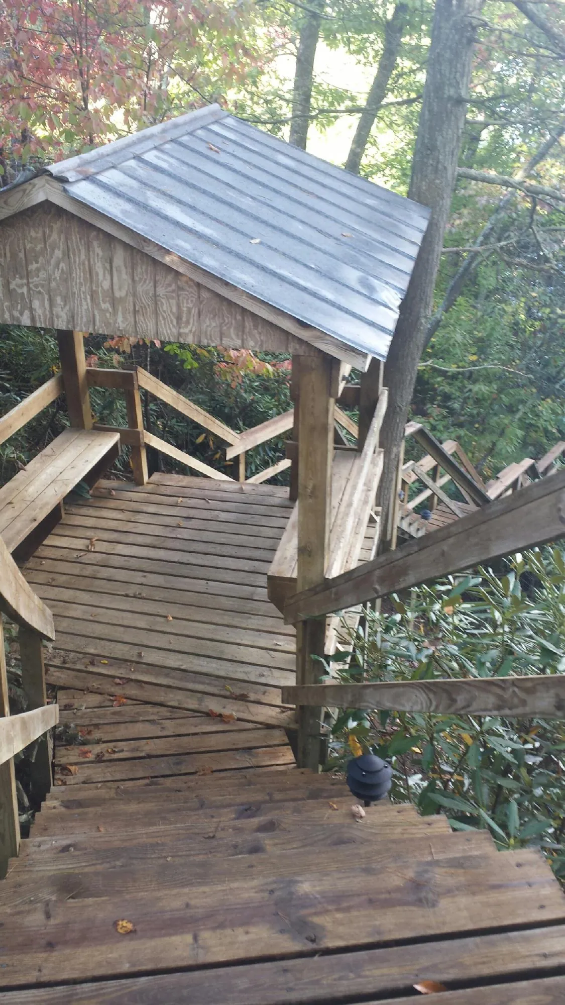 Metal roofed shelter over wooden steps on a wooded walkway — Skylight Repair & Installation work by our crew in Osage City