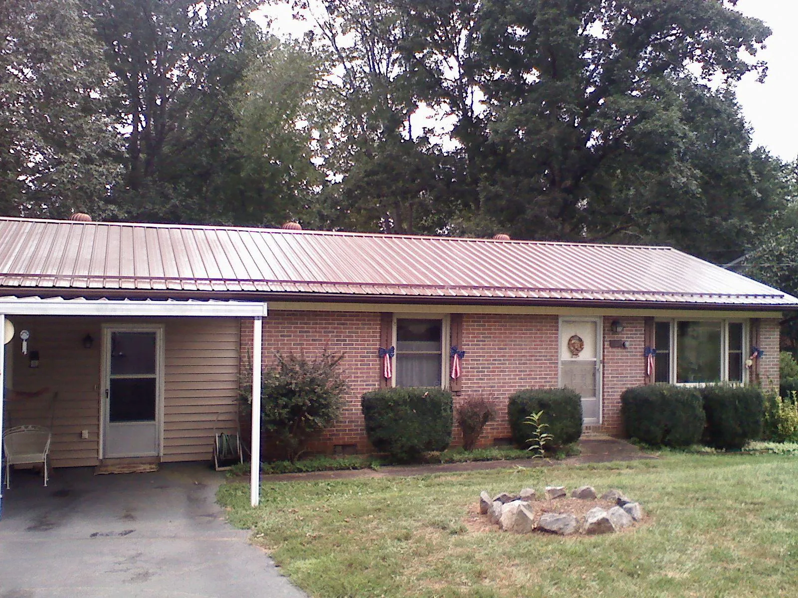 Bronze metal roof and carport on a brick ranch home — Roof Repair work by our crew in Osage City