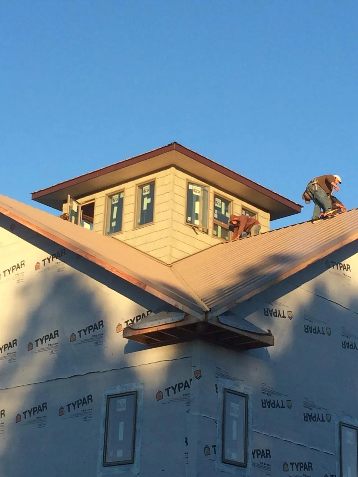 Roofers working around a rooftop cupola on a new metal roof at sunset — Roof Waterproofing in Osage City by Roofing Brothers
